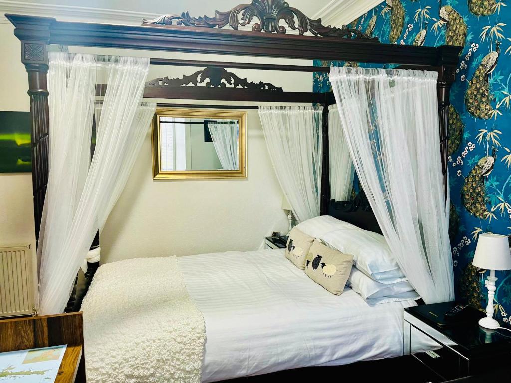 勒威克Norlande的一间卧室配有一张带白色床单和窗帘的床