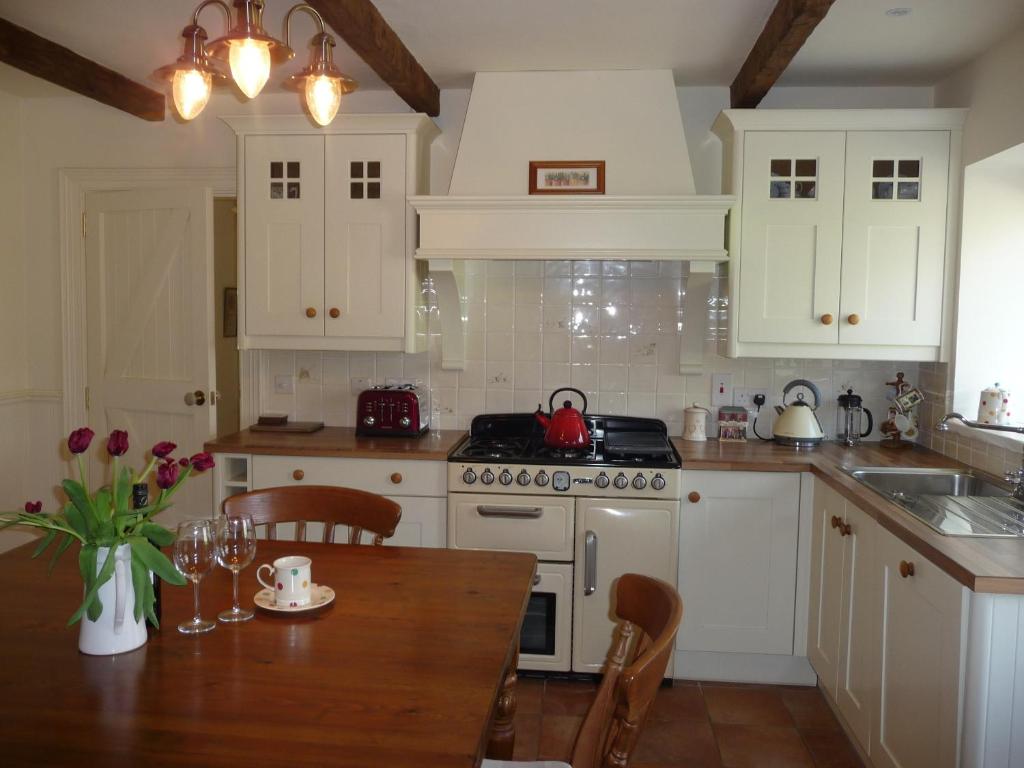 Greencastle山楂度假屋的厨房配有白色橱柜和木桌