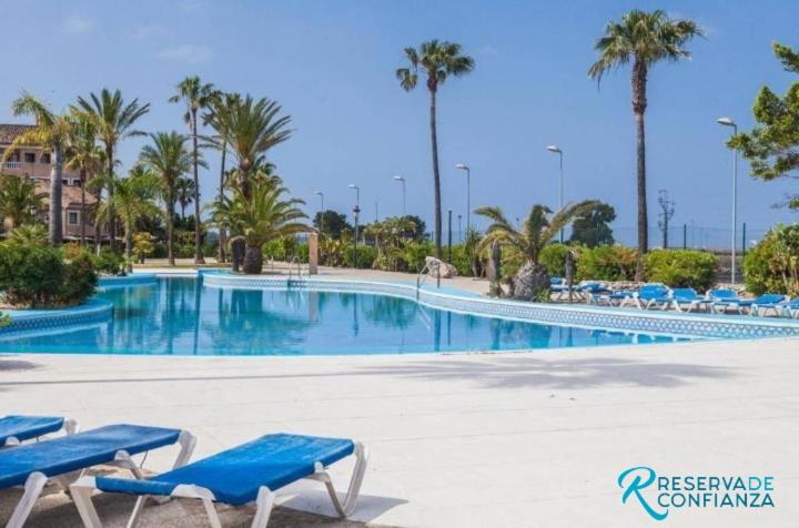 圣费尔南多APTO BAHIA SUR RESERVA DE CONFIANZA的一个带蓝色椅子和棕榈树的大型游泳池