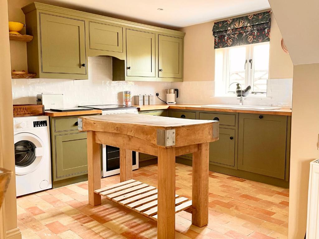 GestingthorpeThe Hayloft的一个带绿色橱柜和木制小岛的厨房
