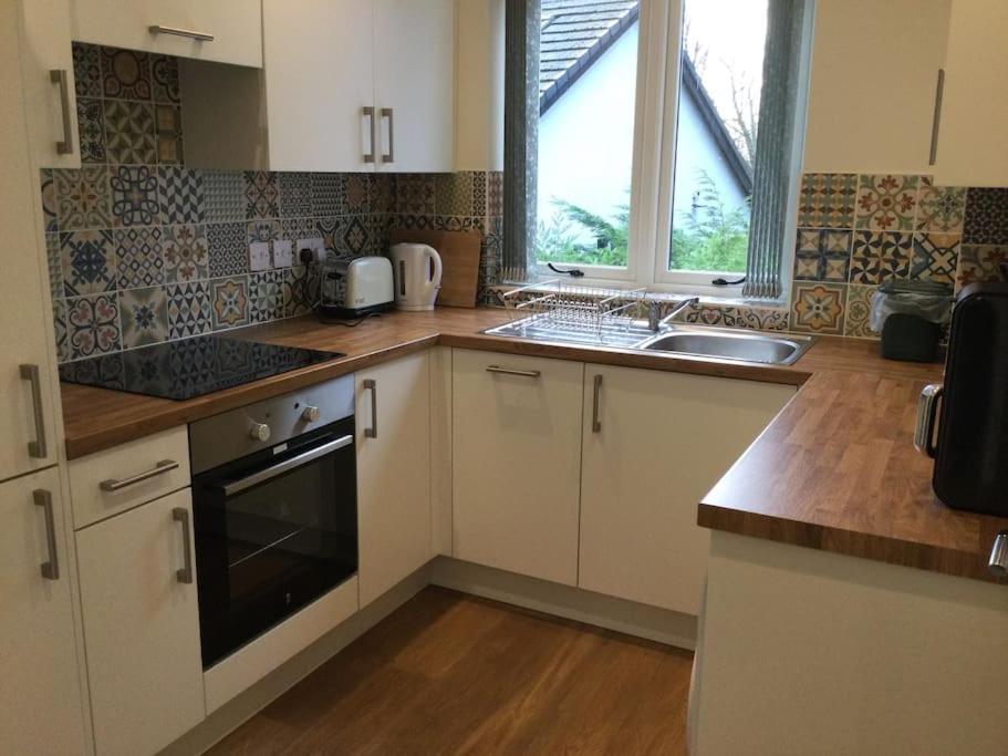 LostockChurstonBnB, private flat within family home, Bolton的厨房配有白色橱柜、水槽和窗户。