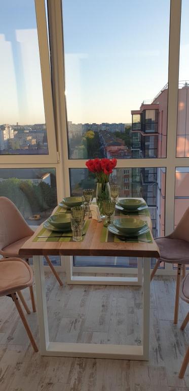 卢茨克Dream town Apartaments біля залізничного вокзалу的阳台上的桌子上摆放着盘子和鲜花
