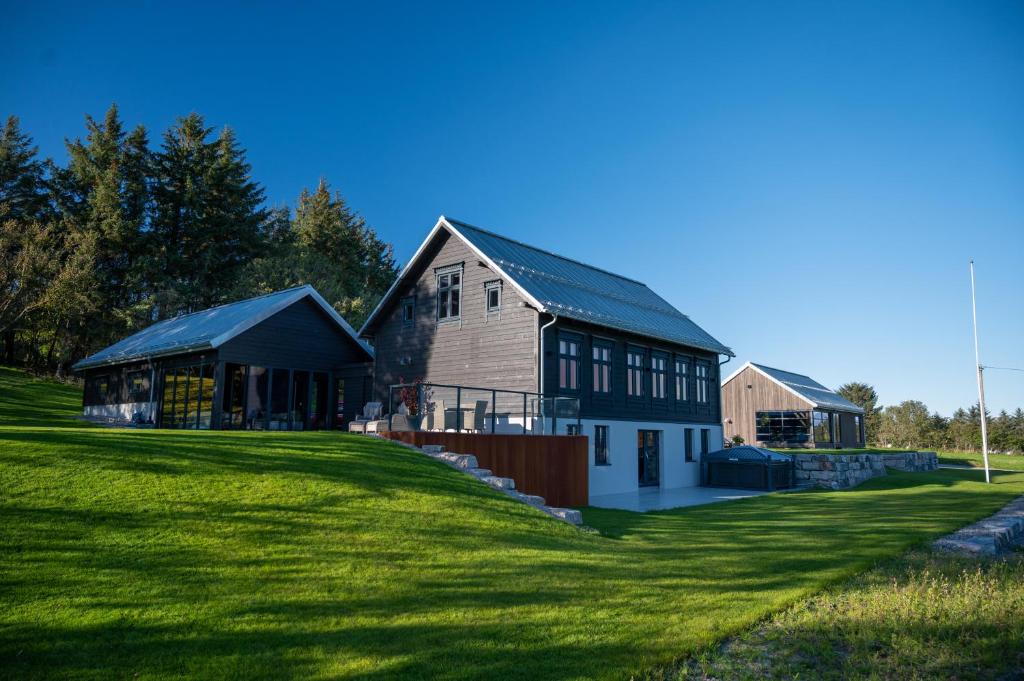 GodøyGodo Lodge的一座大房子,位于一座建筑旁边的草地上