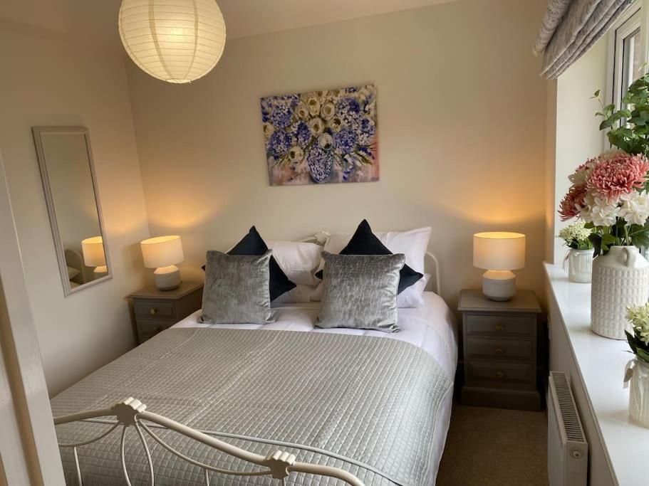 伊利Comfortable new home in Isleham的卧室配有带枕头的床铺和墙上的绘画