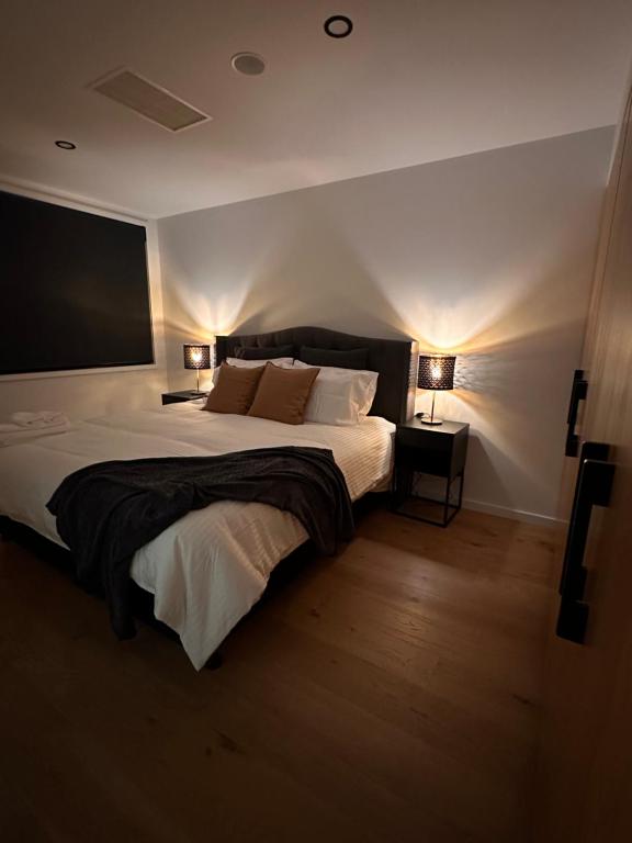 堪培拉Palko - Luxury In the City的一间卧室配有一张带两盏灯的大型白色床。