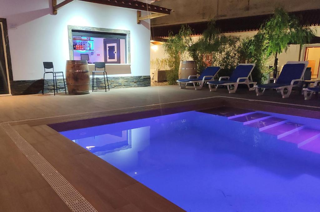 雷根古什-迪蒙萨拉什Luxury Palm Suites的一个带椅子的房间,游泳池里设有蓝色的灯光