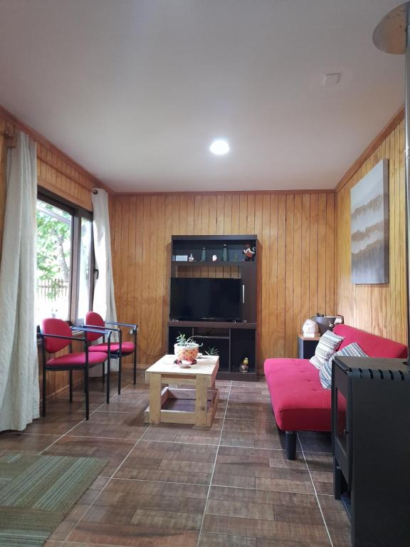 科伊艾科Borde Rio Coyhaique Cabaña y Tinaja的客厅配有红色家具和电视