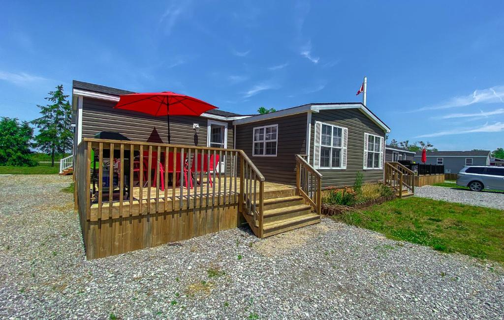 滨湖尼亚加拉Falcon Cottages的一座带甲板和红色遮阳伞的小房子