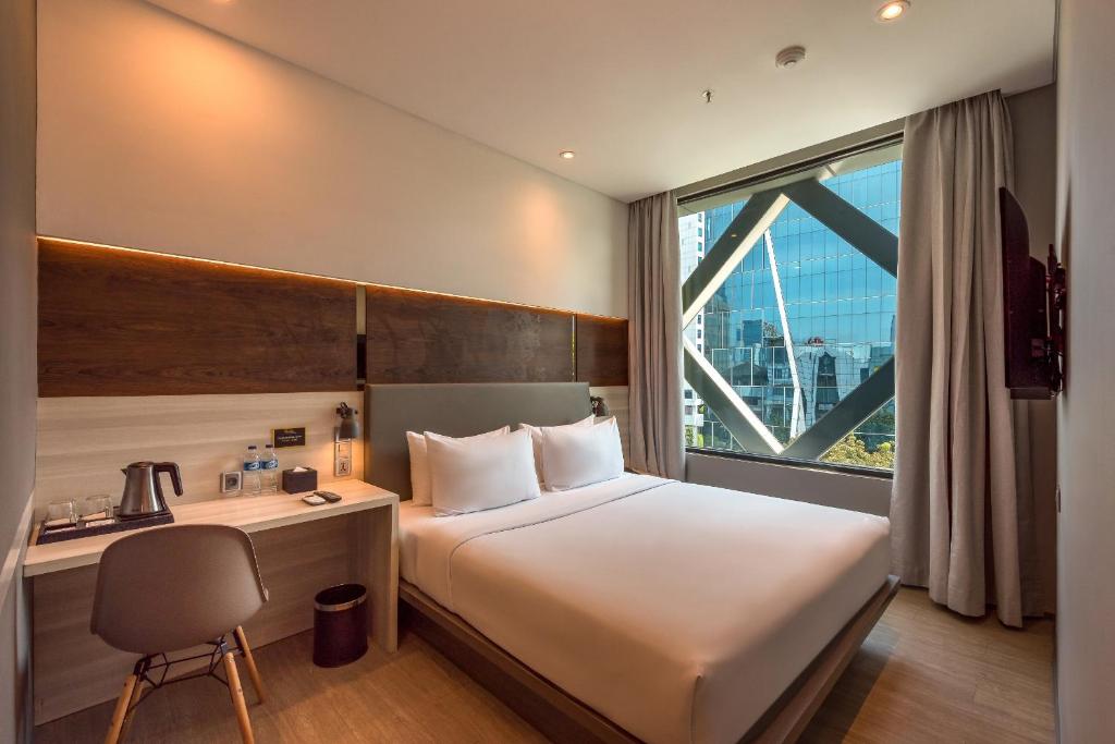 雅加达Stanley Wahid Hasyim Jakarta的配有一张床、一张书桌和一扇窗户的酒店客房