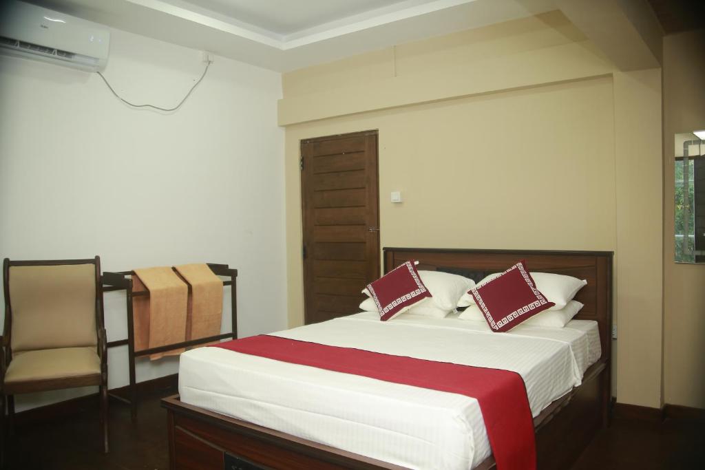阿努拉德普勒Shanthi Villa Resort的一间卧室配有一张大床和一把椅子
