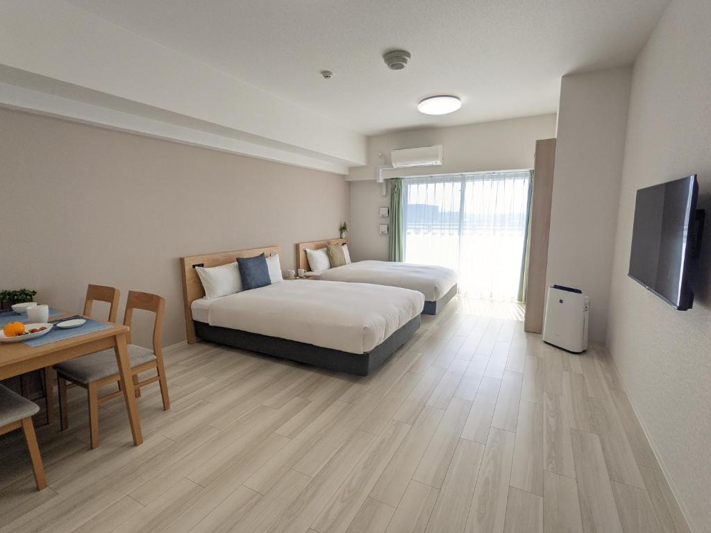 大阪ESLEAD HOTEL Namba Daikokucho的酒店客房设有两张床、一张桌子和电视。