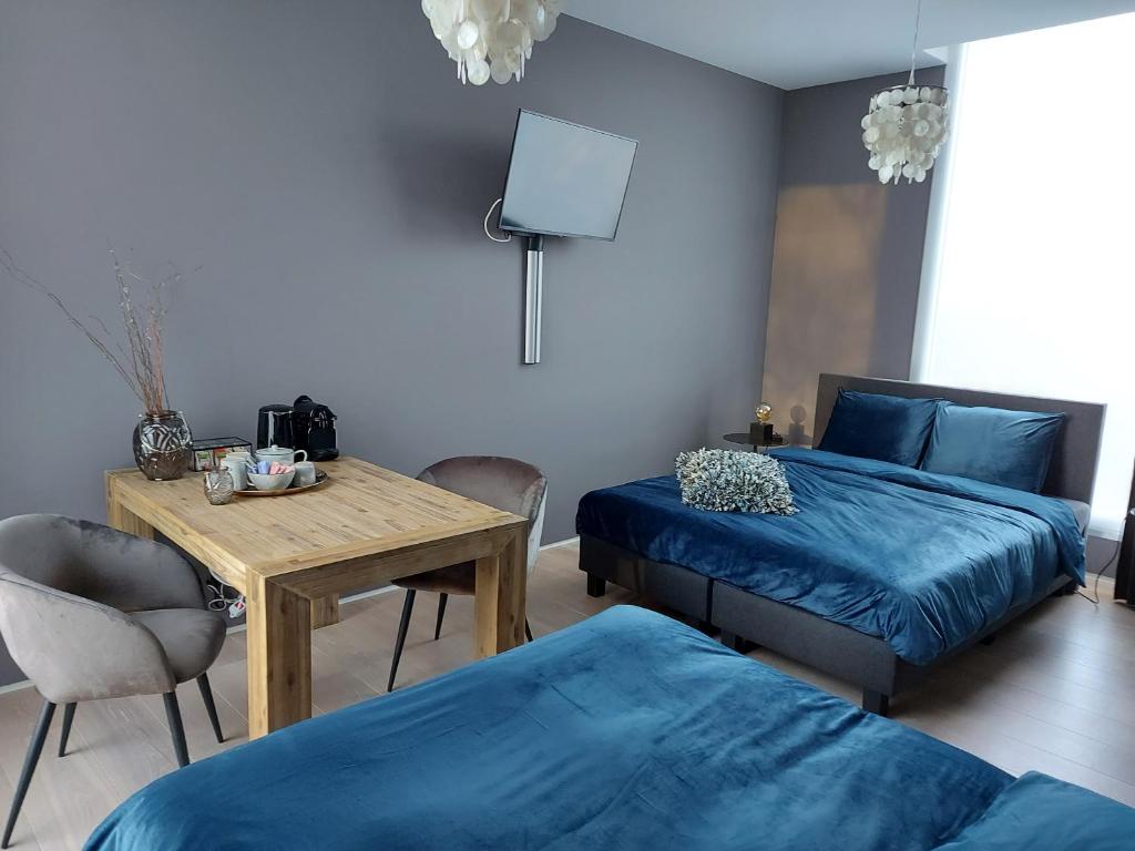 博克斯特尔Bed & Wellness Boxtel, 4 persoonskamer met eigen badkamer的一间卧室配有两张床、一张木桌和一张桌子。