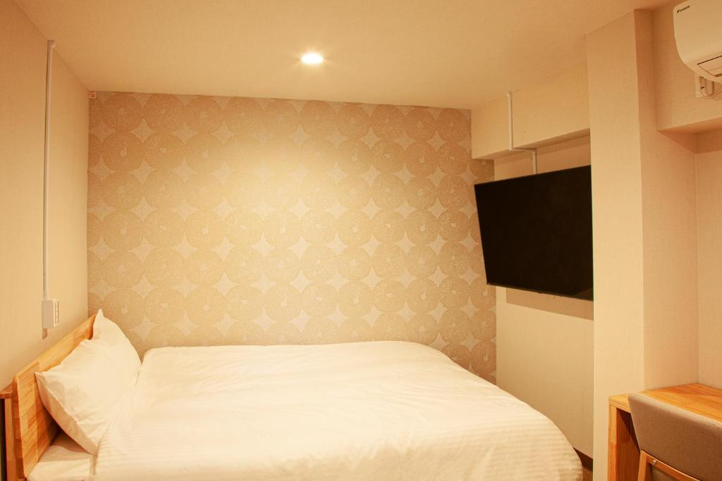 东京Sauna & Cabin Thermae-yu Nishiazabu的卧室配有白色的床和平面电视。
