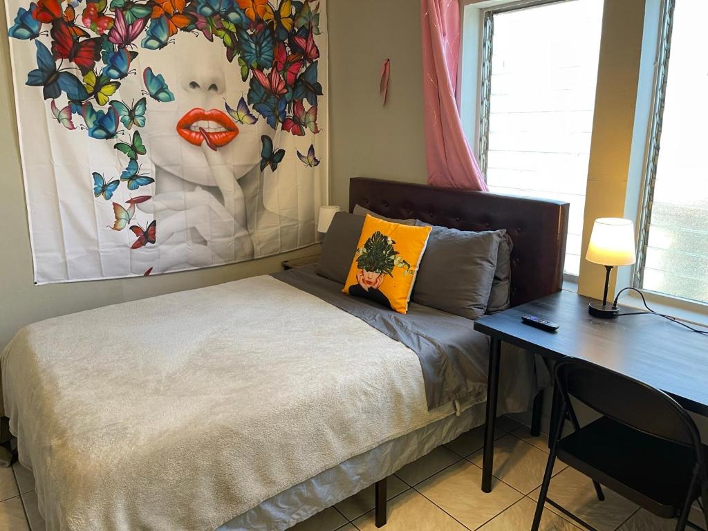 迈阿密Best Value inside City Miami, Near Airport, Beach, Center & Metro的一间卧室配有一张带书桌和绘画的床。
