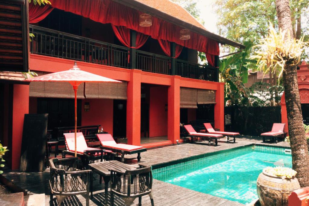 清迈提延那茹殖民饭店的一个带椅子和遮阳伞的游泳池的度假酒店
