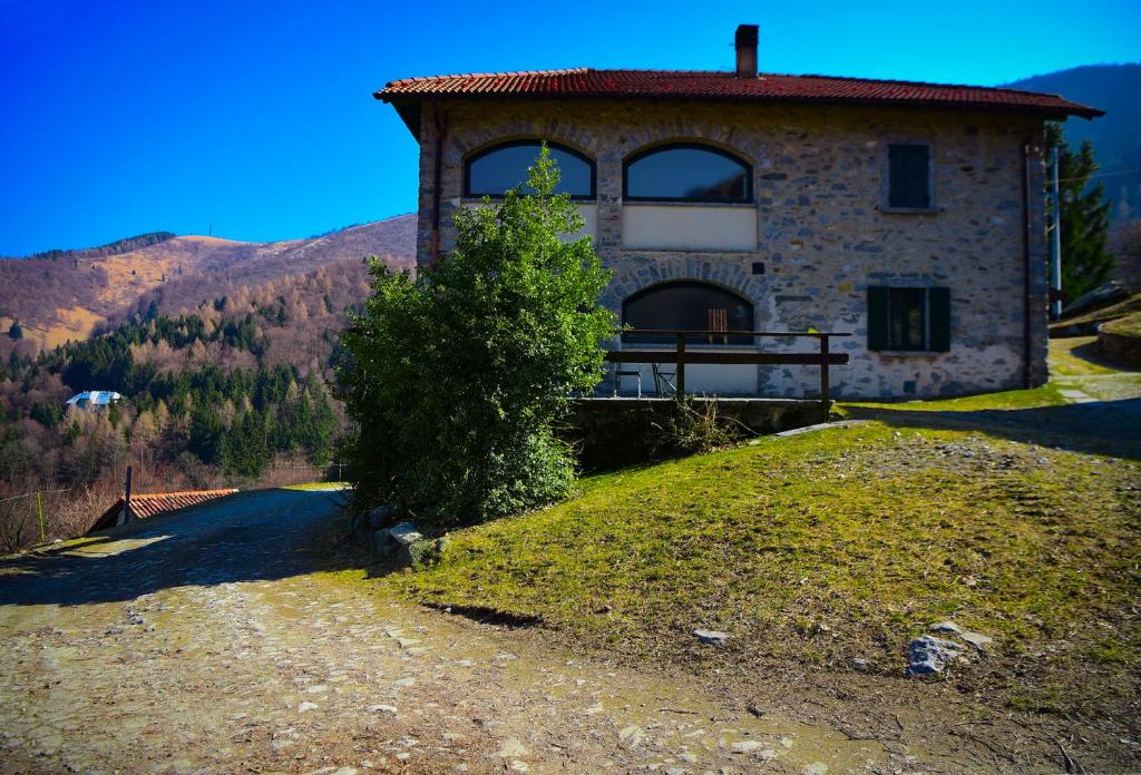 贝拉吉奥Il Larice - Agriturismo Alpe del Ville San Primo by Wonderful Italy的山丘上的房子,前面有一棵树