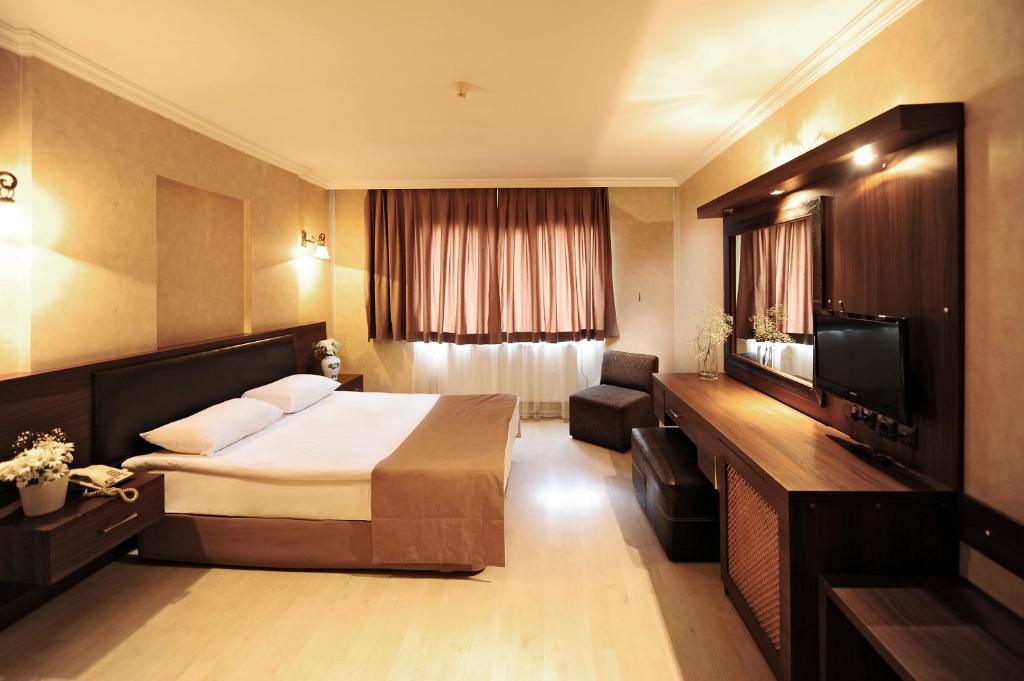 伊兹密尔Üstün Hotel Alsancak的酒店客房,配有床和电视