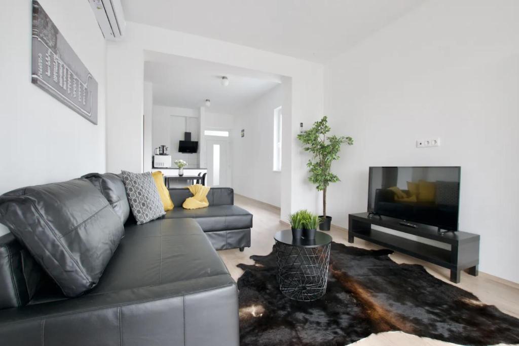 扎马迪Family Apartments by Hi5 - Zamardi的客厅配有黑色真皮沙发和平面电视。