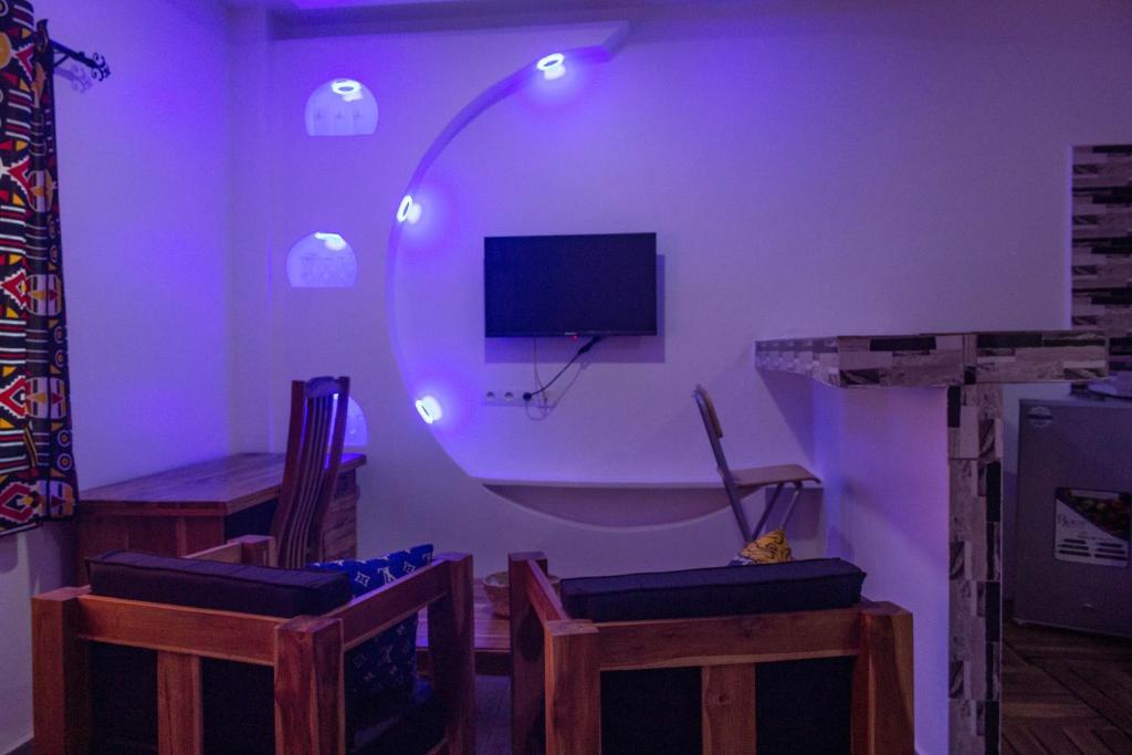 洛美les perles du bonheur Nyékonakpoé的一间紫色客房,配有椅子和电视
