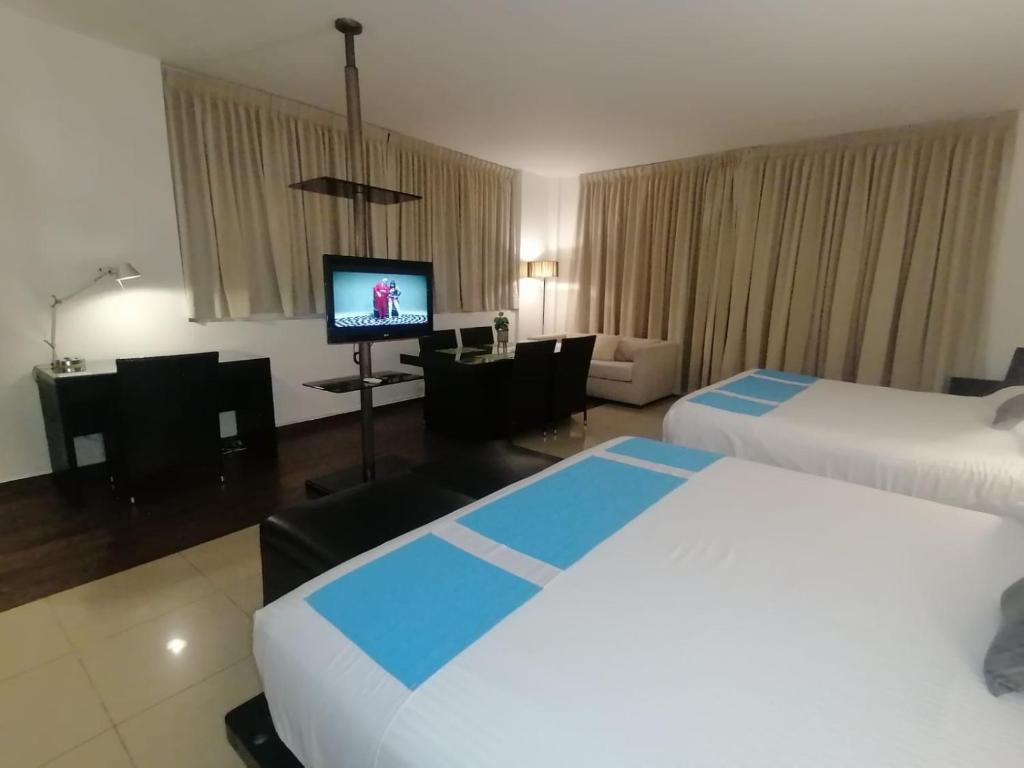 普拉亚布兰卡Town Center Playa Blan的酒店客房设有两张床和一台平面电视。