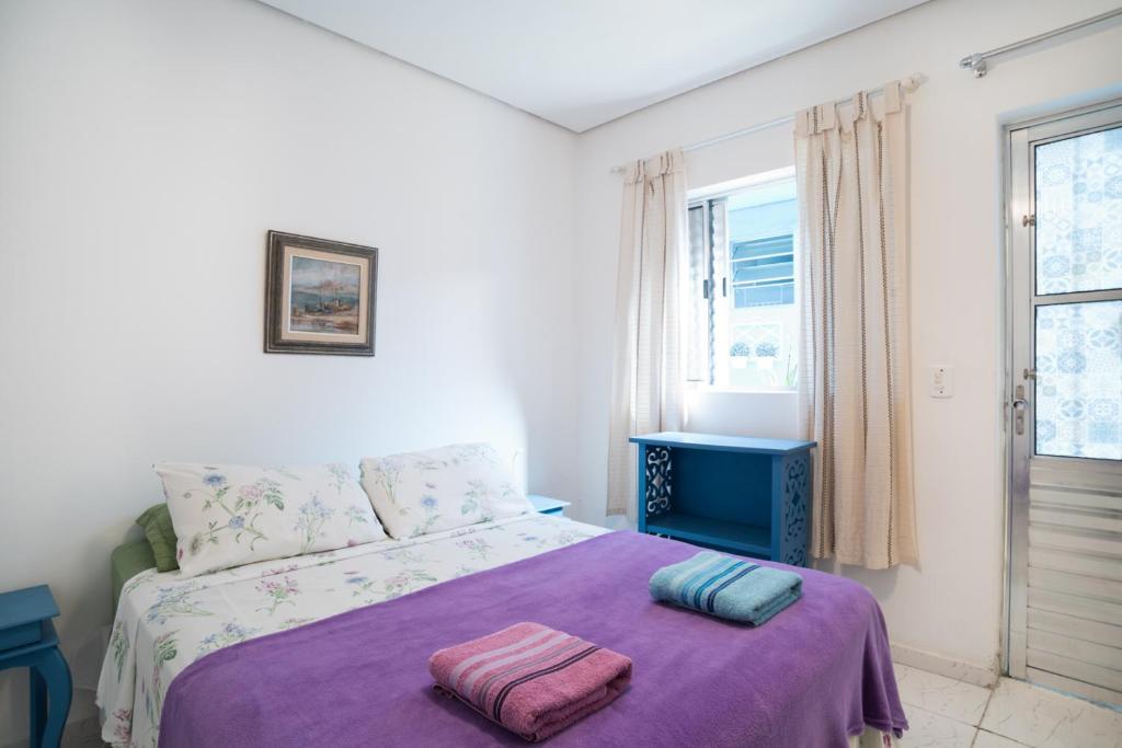 圣保罗Aconchego Azul Suítes Vila Mariana的一间卧室配有一张带紫色毯子的床和窗户。