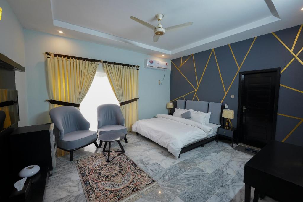 伊斯兰堡SK Residence的一间卧室配有一张床和两把椅子