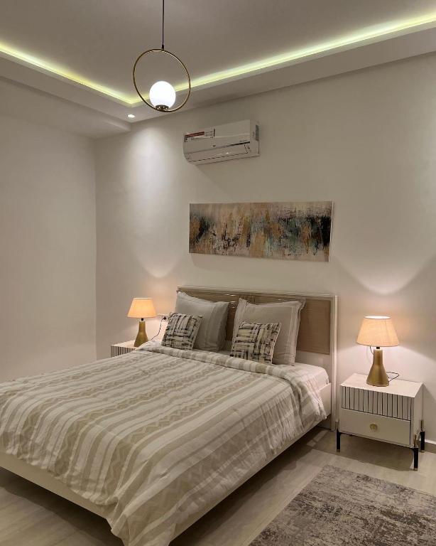 马拉喀什Dar Sanaa Marrakech的白色卧室配有一张带两盏灯的大床