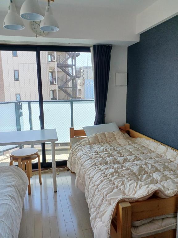 大阪オリエントシティ南堀江Ⅱ的一间卧室配有一张床、一张桌子和一个大窗户