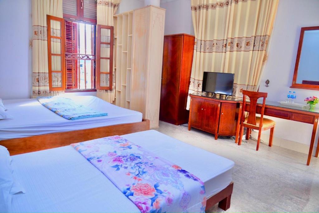 Móng CáiThịnh Nhàn motel的一间卧室配有两张床、一张桌子和一台电视。