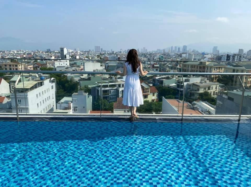 岘港Minh Quan Hotel - Da Nang Center By HOS的站在建筑物边缘的身着白色衣服的女人