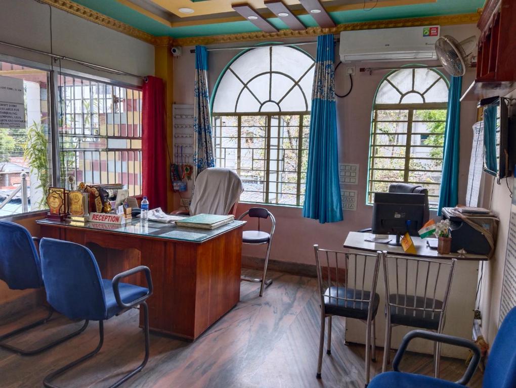 西里古里Bikash Bhawan Lodge的一间设有椅子、书桌和窗户的等候室