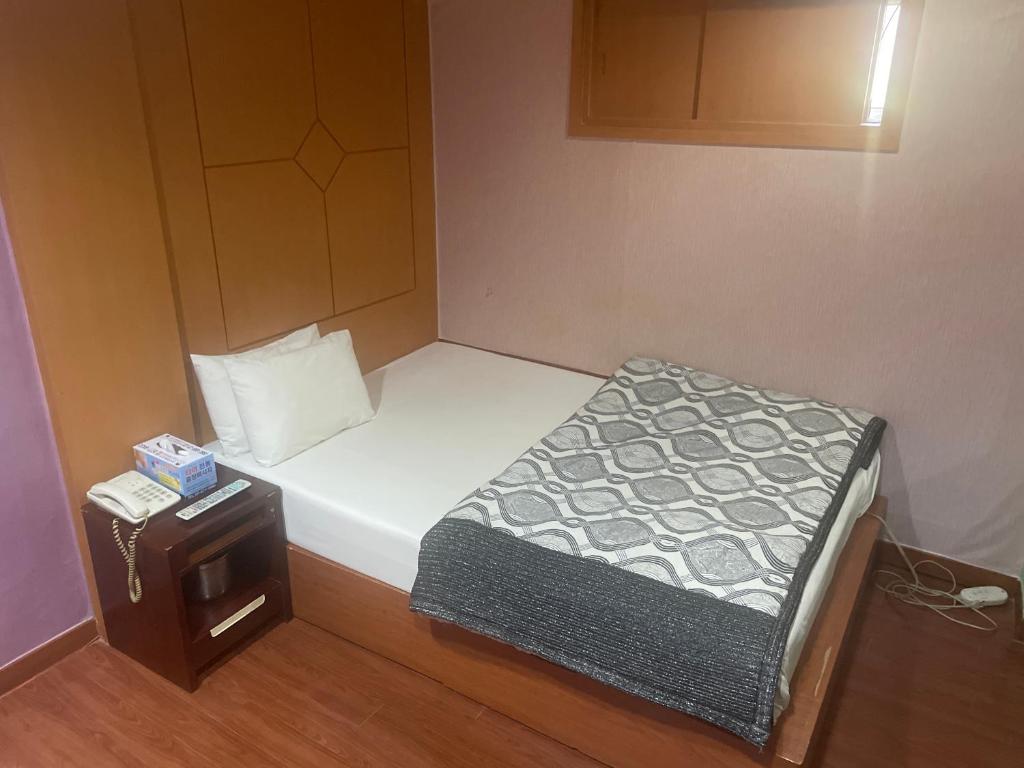 首尔Grace Motel的小房间,设有床和床头柜