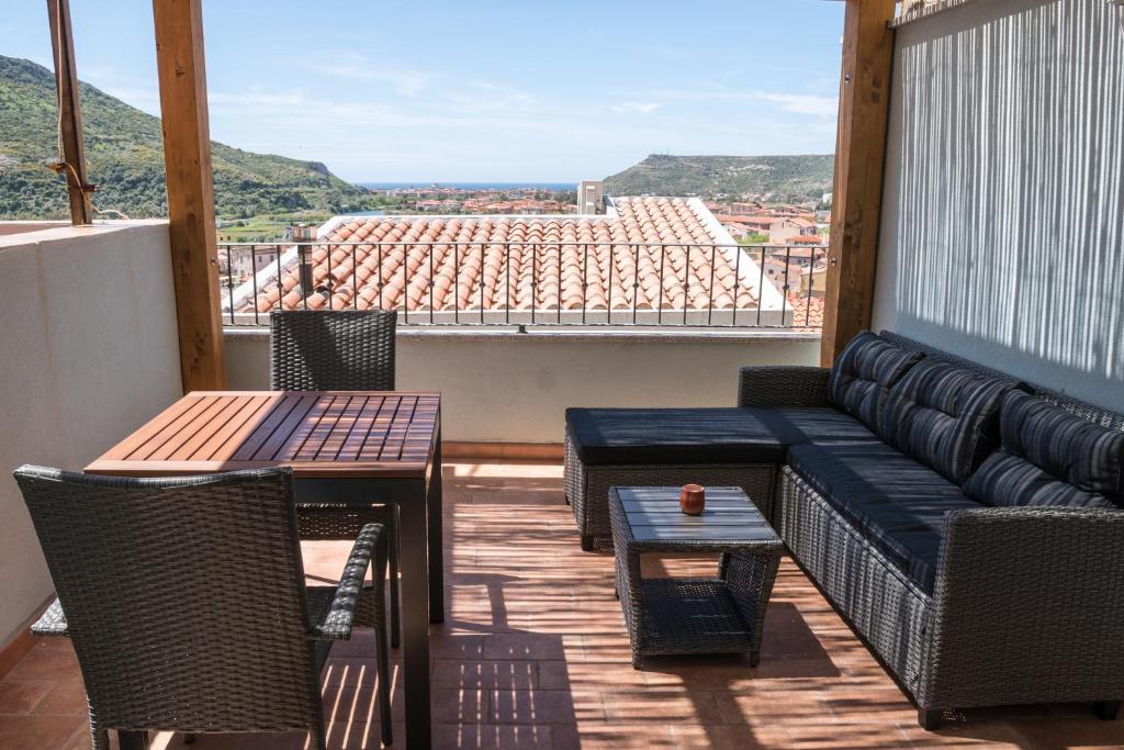 博萨Belvedere - Terrazza panoramica的阳台配有沙发和桌子,享有美景。
