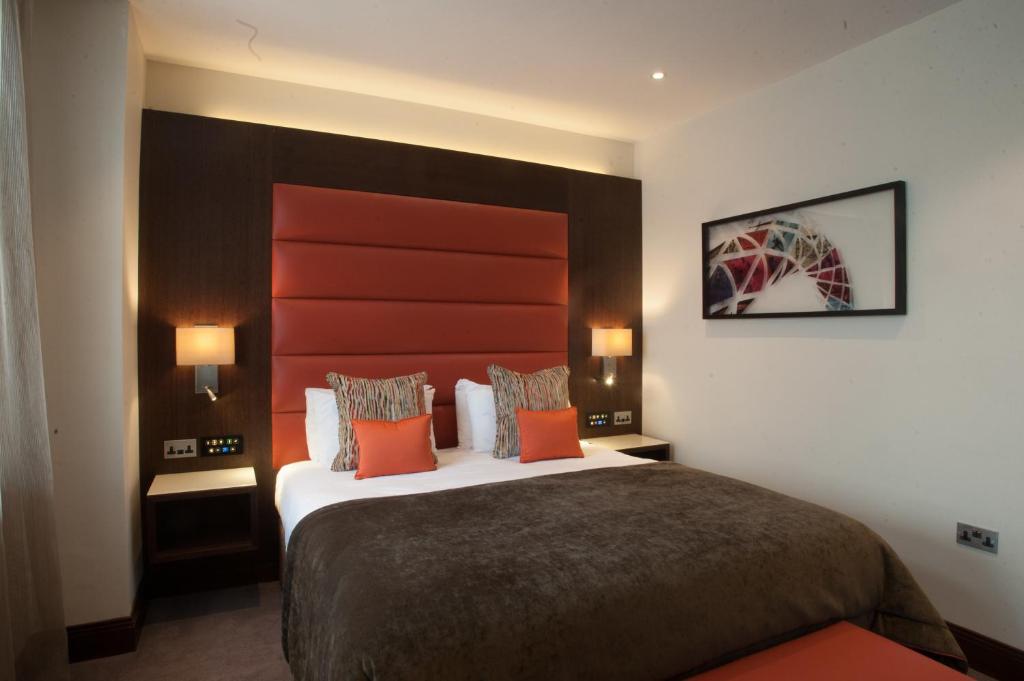 伦敦温布利圣乔治酒店的酒店客房配有一张带橙色枕头的大床