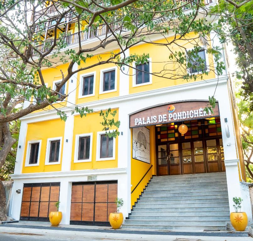 蓬蒂切里Palais de Pondichéry的一座黄色的建筑,上面有读过Palascio的Poloshenko的标志