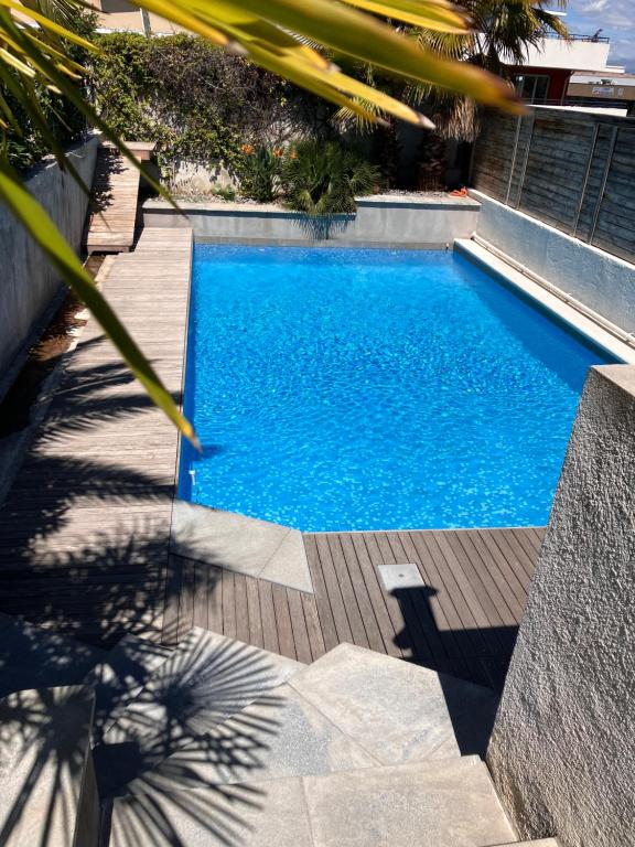 卢贝新城2 pièces rez-de-jardin dans maison avec piscine的一个带木甲板的庭院内的游泳池