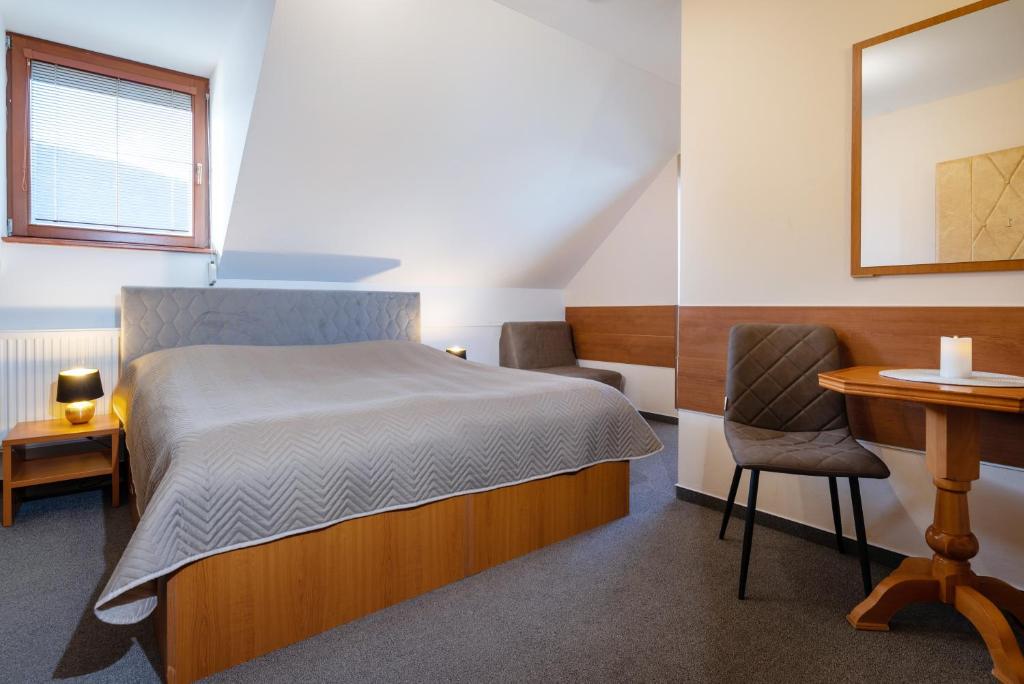 劳耶克特普利采维拉维克托利亚酒店的一间卧室配有一张床、一张桌子和一把椅子