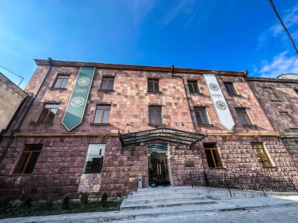 久姆里KUMA Hotel Gyumri的一座大型砖砌建筑,有两个标志