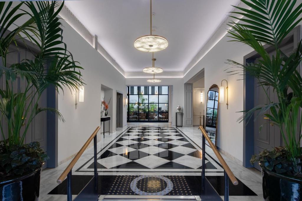 里雄莱锡安Rephael House Boutique Hotel的走廊上设有黑白瓷砖地板和盆栽植物