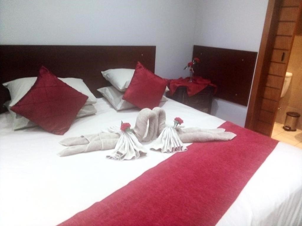 丹地Amabutho Warrior Lodge的一张带白色毛巾和红色枕头的床
