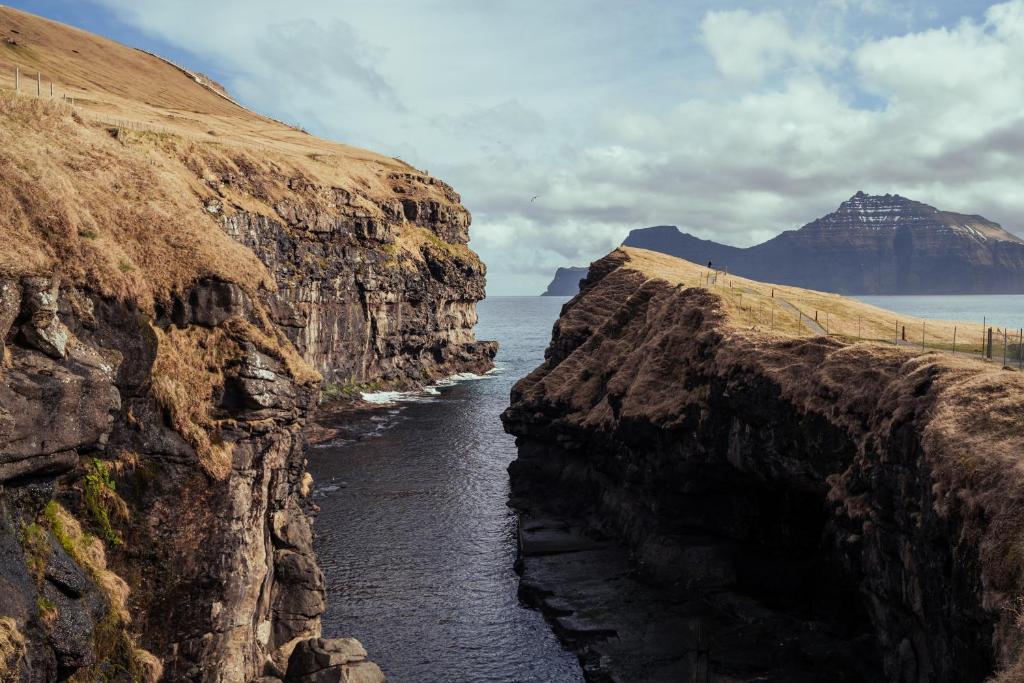 Við GjógvCozy Cottage / 3BR / Hiking / Nature的一条穿过海边岩石峭壁的河流