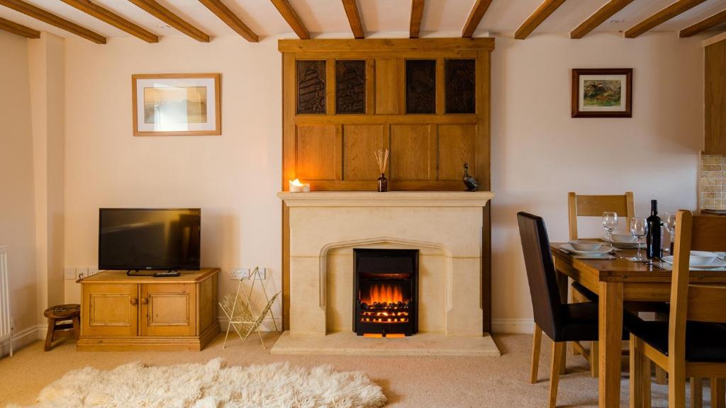 奇平卡姆登Old Mill Barn的客厅设有壁炉、桌子和电视
