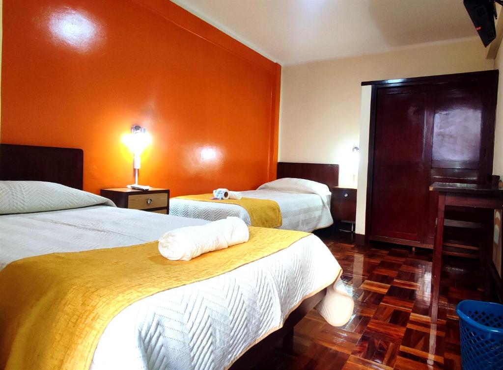 拉巴斯Hotel Express的橙色墙壁的酒店客房内的两张床
