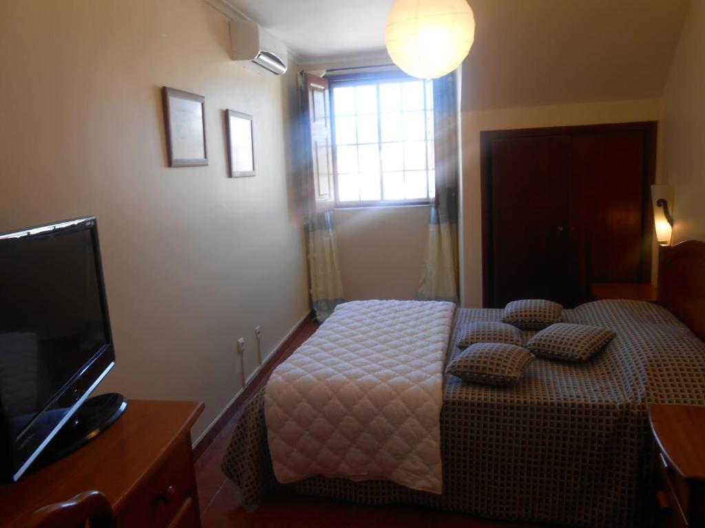 克卢什Apartamentos Turisticos Queluz的一间卧室配有带枕头的床铺和电视。