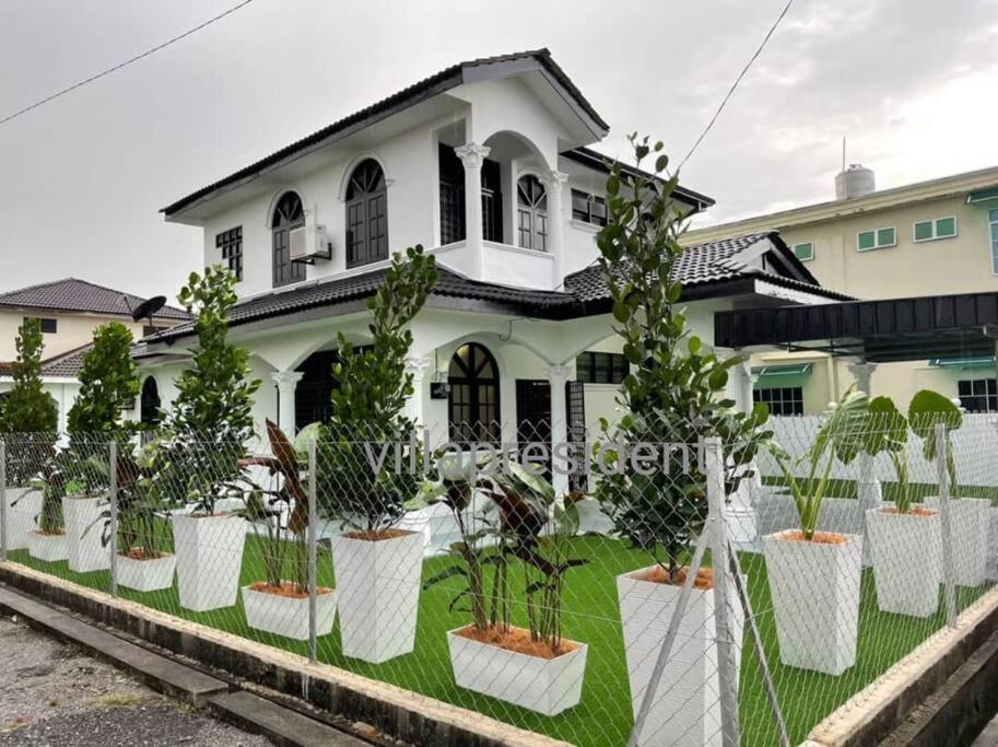 Kampung KerangiVilla President Homestay -4 bedroom Aircond WIFI Vacations Home的前面有盆栽植物的白色房子