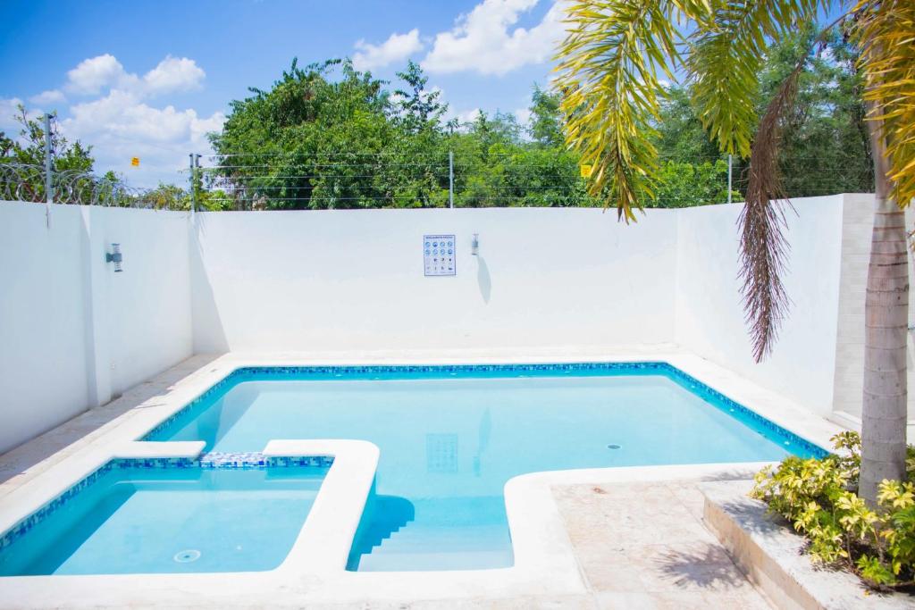 圣地亚哥洛斯卡巴3 BR apartment ciudad santiago de los caballeros的棕榈树白色围栏旁边的游泳池