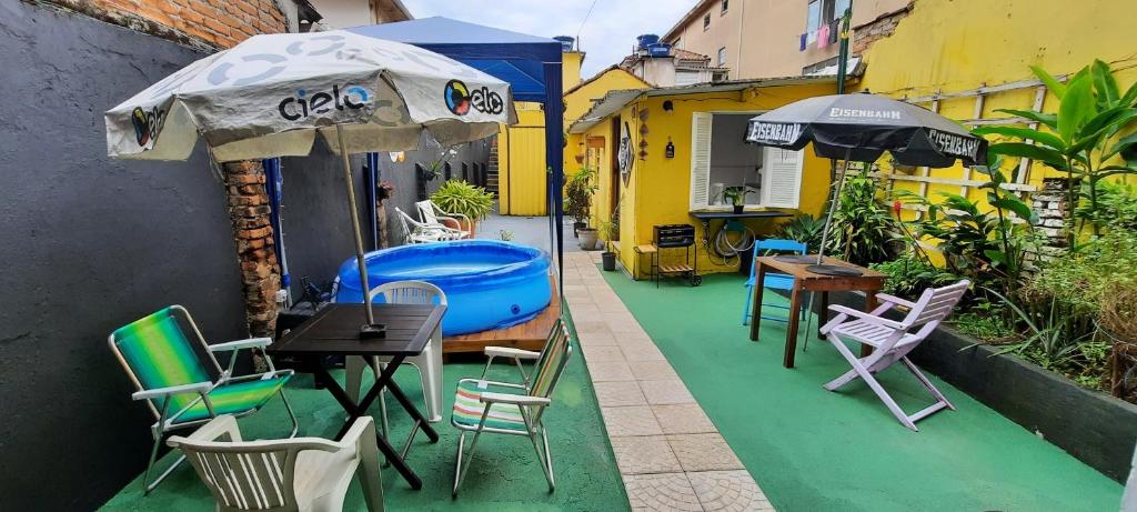 桑托斯Quintal da Bella Hostel的庭院配有桌椅和遮阳伞。