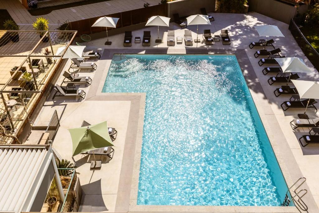 佩皮尼昂Holiday Inn Perpignan, an IHG Hotel的享有带椅子和遮阳伞的游泳池的上方景色