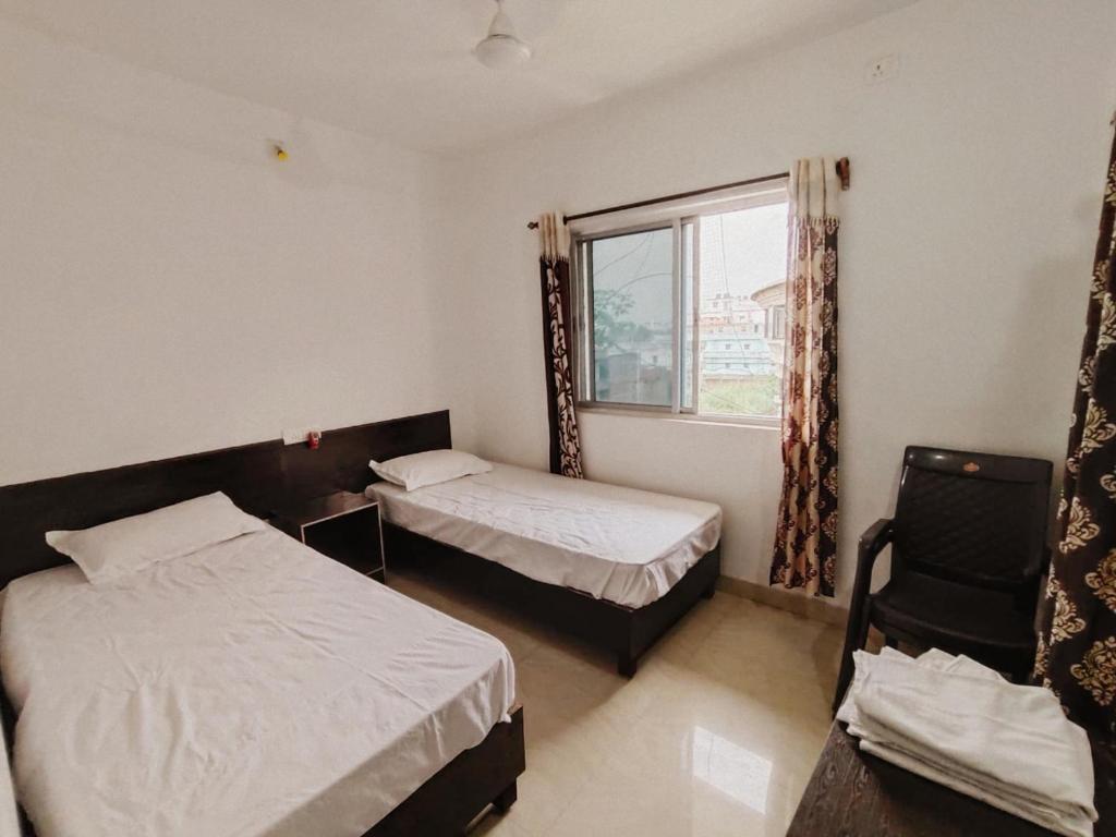菩提伽耶Dwarka Home Stay的一间卧室设有两张床、一个窗口和椅子