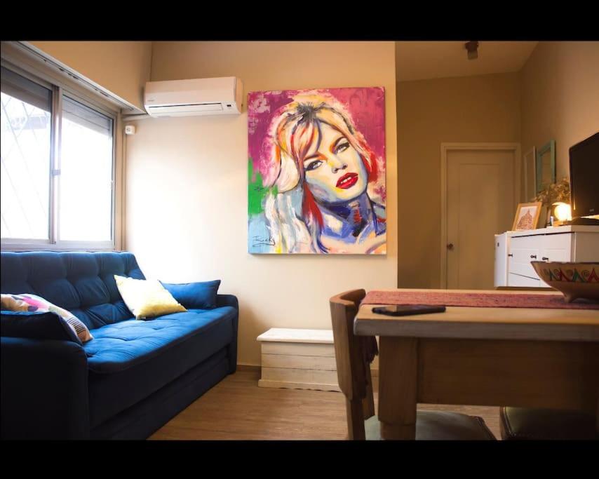 蒙得维的亚Apartamento independiente en alquiler En casa de familia的客厅配有蓝色的沙发和墙上的绘画